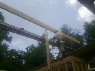 Carpenter setting a ridge beam over a new addition frame — Ice Dam Removal by Roofing Brothers in Grenada