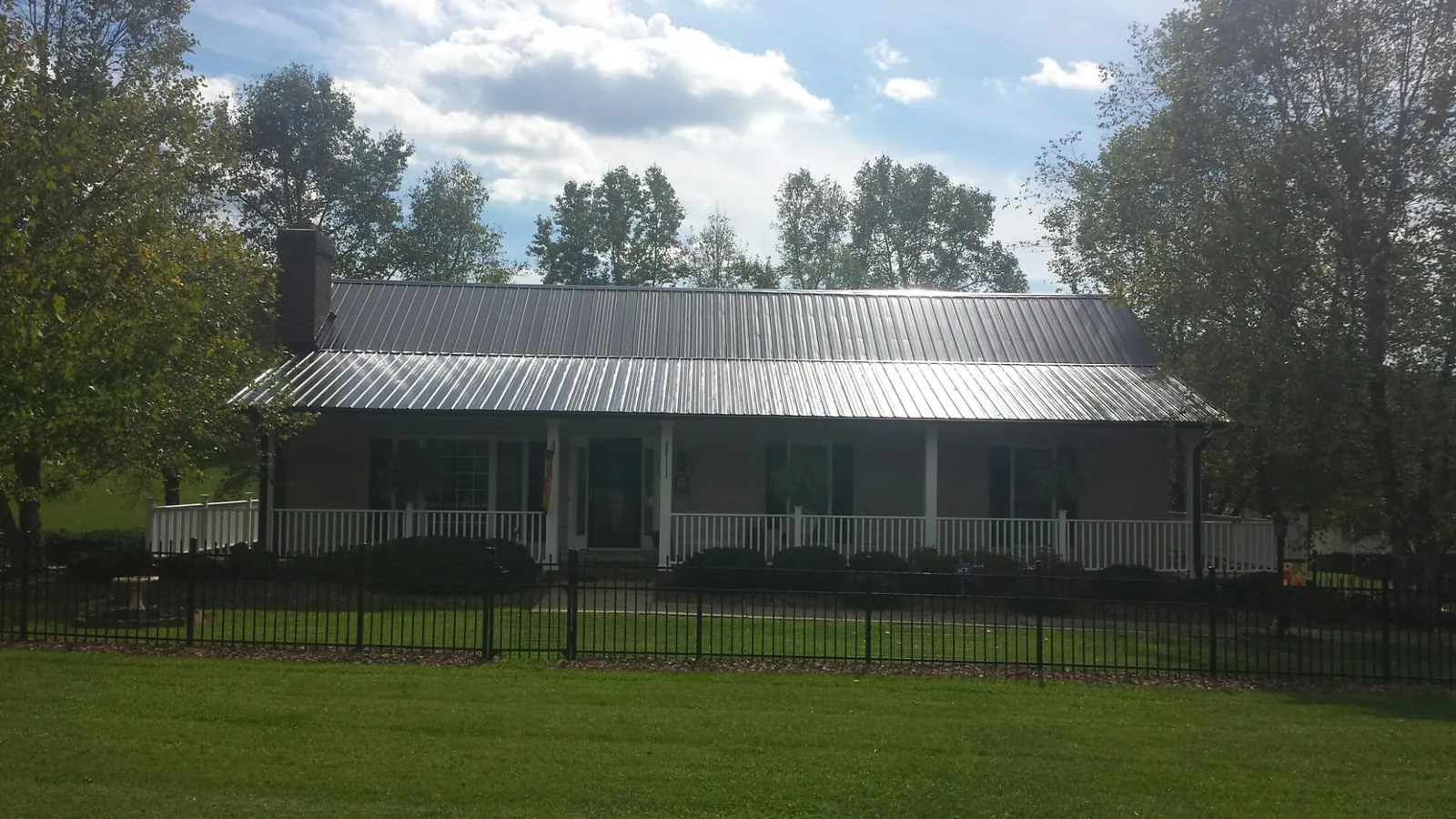 Gray metal roof on a brick ranch with a full width front porch — Gutter Guard Installation work by our crew in Grenada